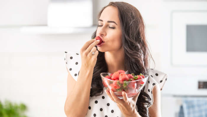 Essen mit Genuss - eine Frau genießt Erdbeeren