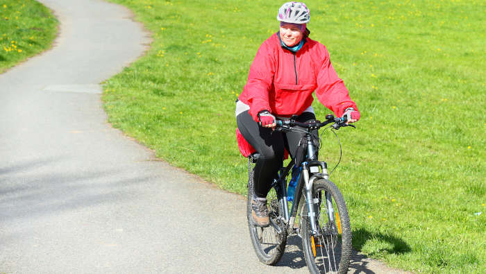 Eine Frau fährt Rad. Mit Helm. Mit einem Rad fahren Trainingsplan für Anfänger
