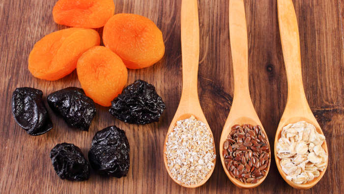 Müsli-Zutaten: getrocknete Aprikosen und Pflaumen, Haferkleie, Leinsaat und Haferflocken