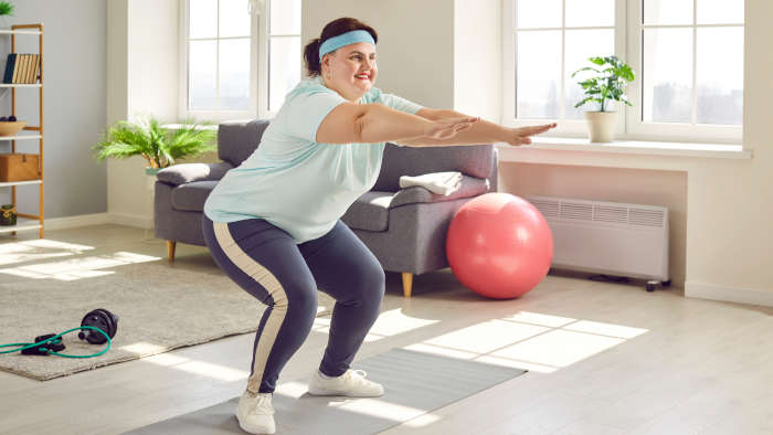 Home Workout - übergewichtige Frau macht Kniebeugen